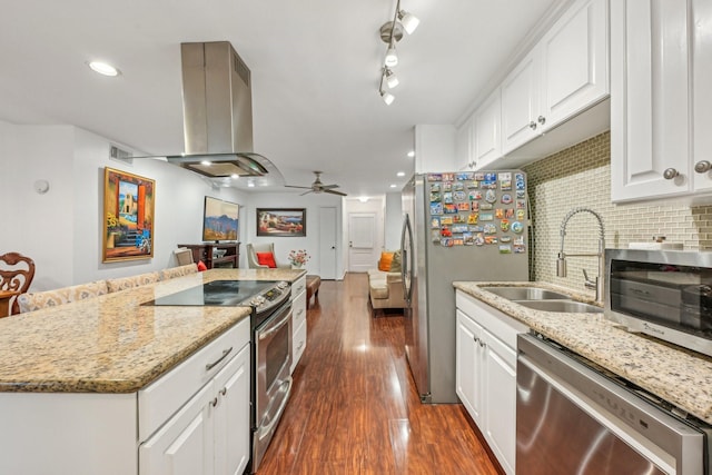 kitchen with island exhaust hood, appliances with stainless steel finishes, decorative backsplash, ceiling fan, and white cabinetry