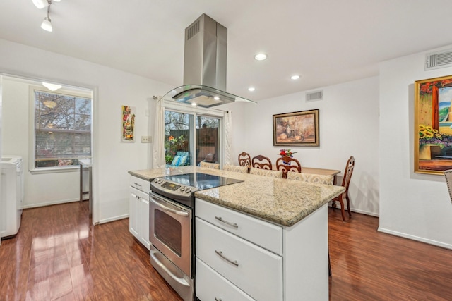 kitchen featuring light stone countertops, island exhaust hood, electric stove, white cabinets, and washer and dryer