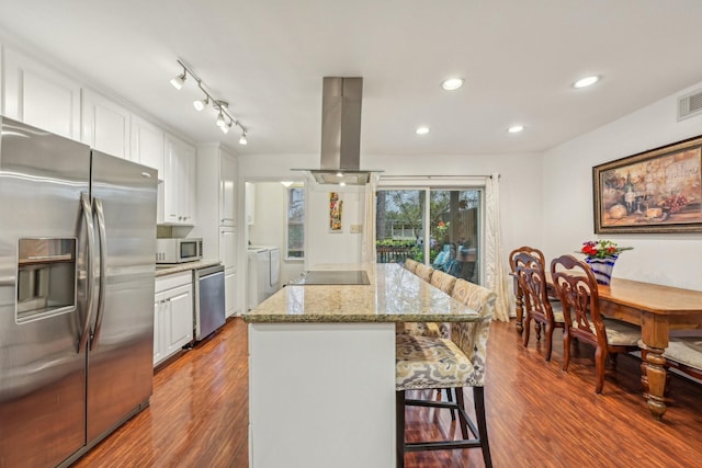 kitchen with white cabinets, appliances with stainless steel finishes, island range hood, and a kitchen island