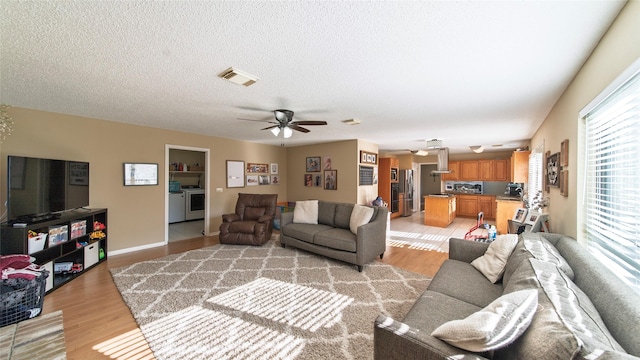 living room with a textured ceiling, light hardwood / wood-style flooring, and ceiling fan