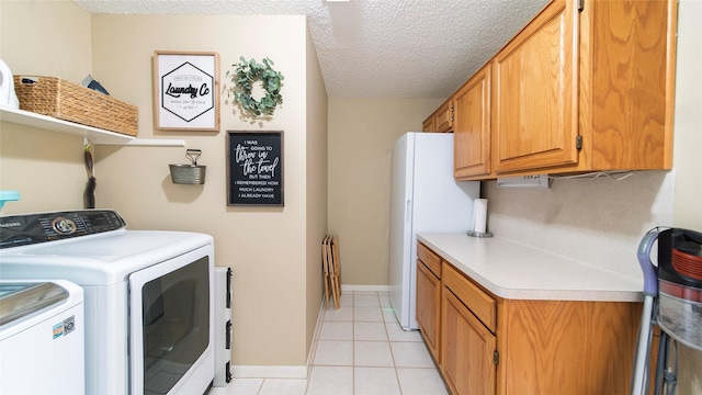 laundry area featuring light tile patterned floors, cabinets, a textured ceiling, and independent washer and dryer