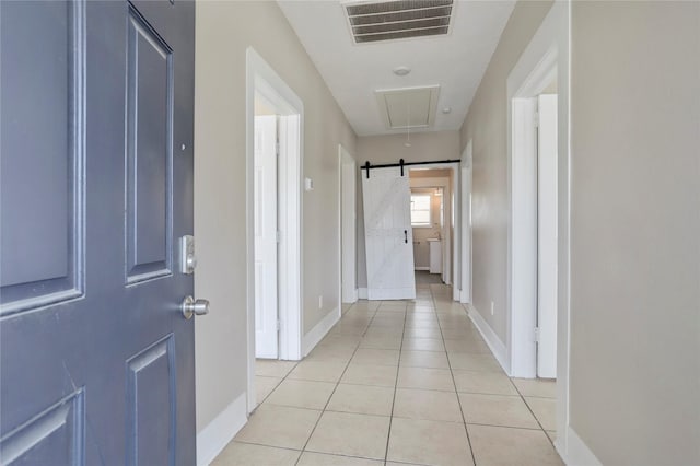 hallway featuring a barn door and light tile patterned floors