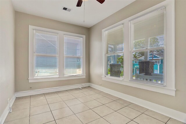 spare room featuring light tile patterned floors, ceiling fan, and a healthy amount of sunlight