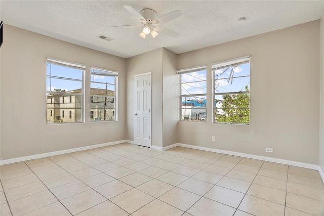 tiled empty room featuring ceiling fan and a textured ceiling