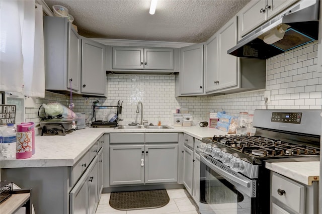 kitchen featuring gas range, decorative backsplash, sink, and gray cabinetry