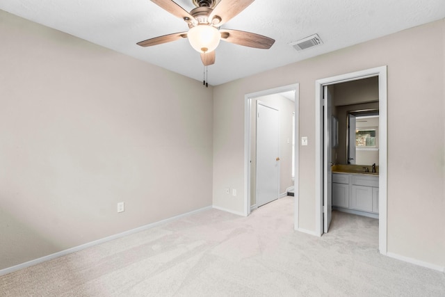 unfurnished bedroom featuring ceiling fan, light colored carpet, ensuite bathroom, and sink