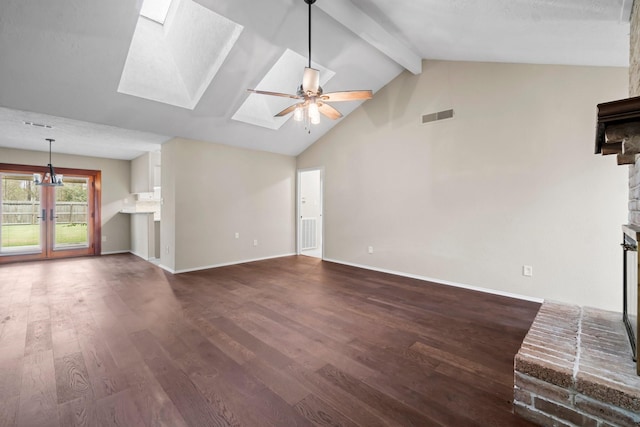 unfurnished living room with beam ceiling, a skylight, ceiling fan, dark wood-type flooring, and a brick fireplace