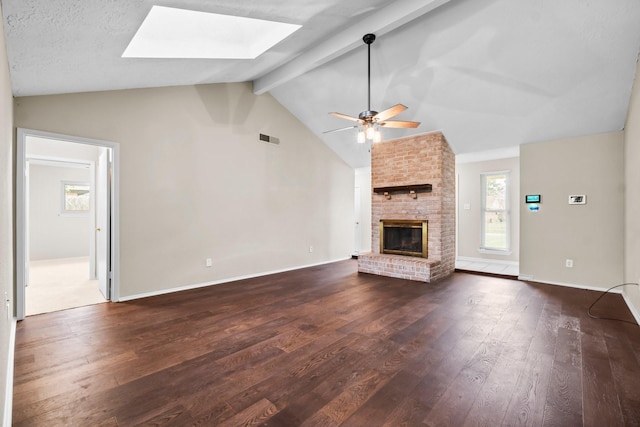 unfurnished living room featuring vaulted ceiling with skylight, a fireplace, and dark wood-type flooring