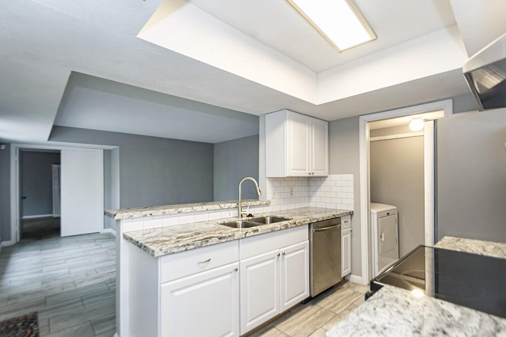 kitchen featuring sink, white cabinetry, stainless steel appliances, independent washer and dryer, and kitchen peninsula