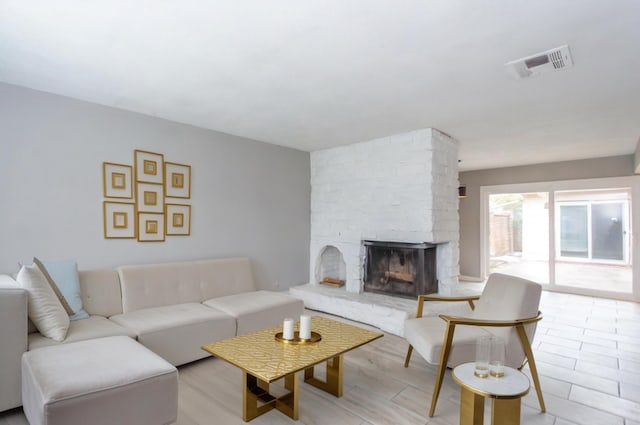 living room featuring a stone fireplace and light hardwood / wood-style flooring