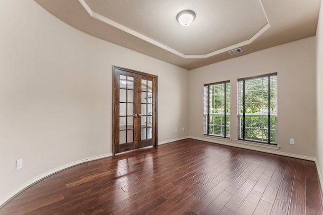 spare room featuring french doors, dark hardwood / wood-style floors, and a raised ceiling