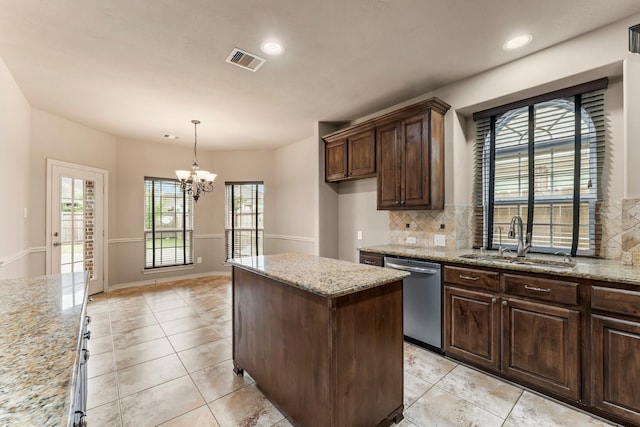 kitchen with sink, light stone counters, stainless steel dishwasher, pendant lighting, and decorative backsplash