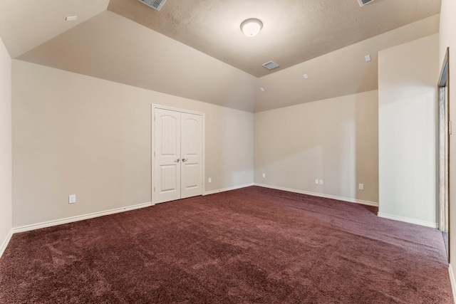 unfurnished room with lofted ceiling and dark colored carpet