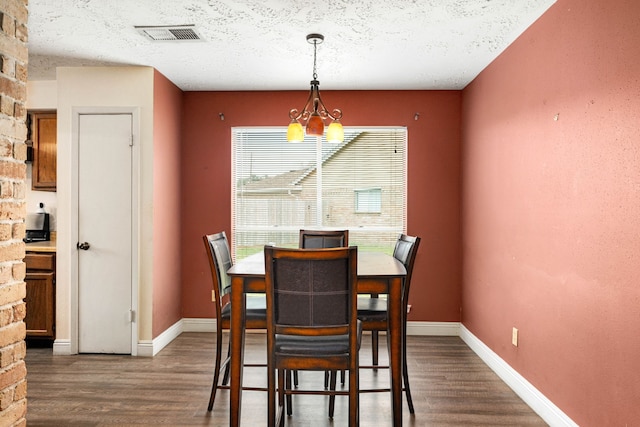 dining room with dark hardwood / wood-style flooring, a textured ceiling, and a notable chandelier