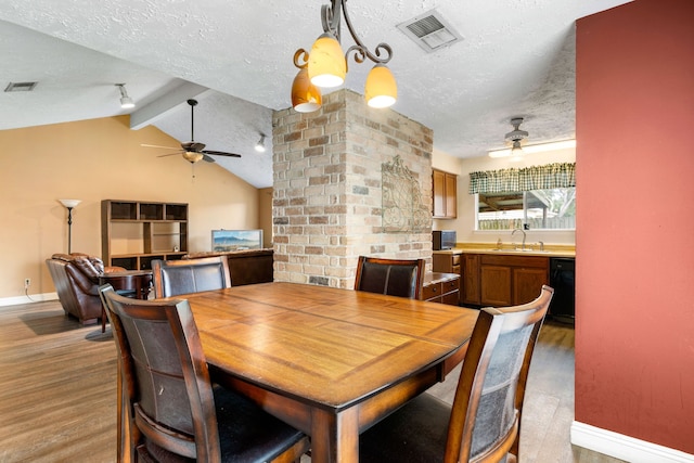 dining area featuring sink, vaulted ceiling with beams, a textured ceiling, hardwood / wood-style flooring, and ceiling fan