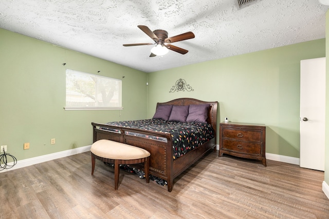 bedroom featuring ceiling fan, a textured ceiling, and light wood-type flooring