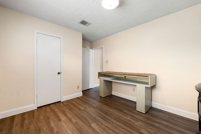 interior space with a textured ceiling and dark hardwood / wood-style flooring