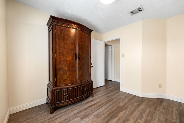 empty room with wood-type flooring and a textured ceiling