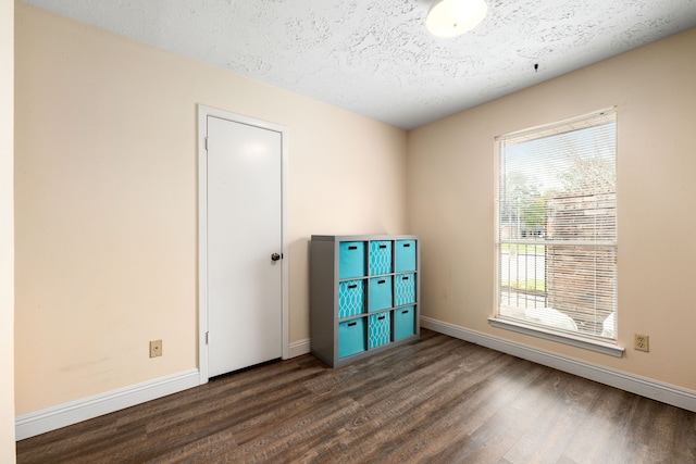 unfurnished room featuring dark wood-type flooring and a textured ceiling