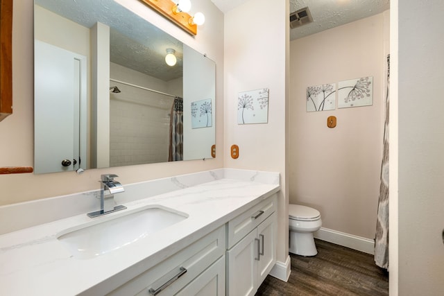 bathroom with curtained shower, hardwood / wood-style floors, vanity, toilet, and a textured ceiling