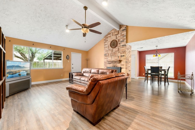 living room with light hardwood / wood-style flooring, ceiling fan, a textured ceiling, a brick fireplace, and beamed ceiling