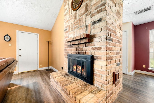 living room featuring a fireplace, dark hardwood / wood-style floors, a textured ceiling, and vaulted ceiling