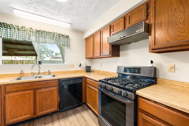 kitchen featuring stainless steel range with gas cooktop, dishwasher, sink, a textured ceiling, and light hardwood / wood-style flooring