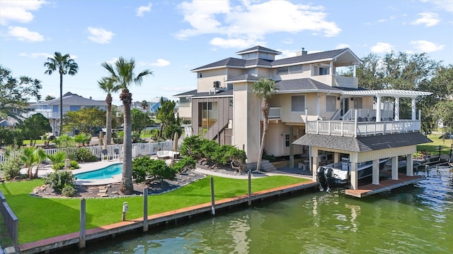 rear view of property featuring a yard, a water view, a fenced in pool, and a balcony