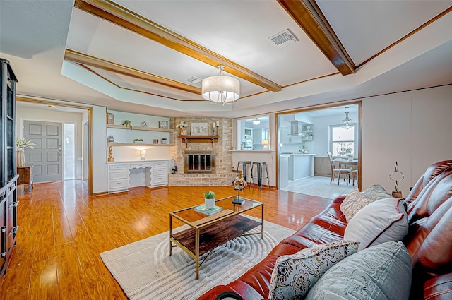 living room featuring beam ceiling, a fireplace, built in features, and hardwood / wood-style flooring