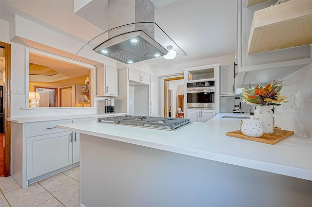 kitchen with kitchen peninsula, appliances with stainless steel finishes, island range hood, sink, and light tile patterned flooring