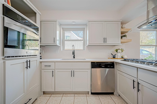 kitchen featuring light tile patterned flooring, appliances with stainless steel finishes, white cabinetry, and sink