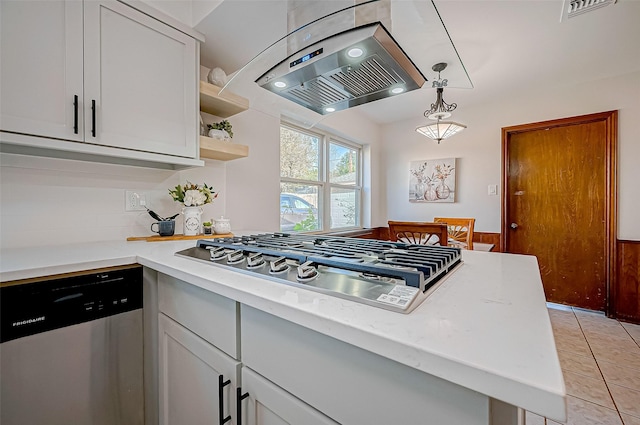 kitchen with white cabinetry, stainless steel appliances, decorative light fixtures, island range hood, and light tile patterned floors