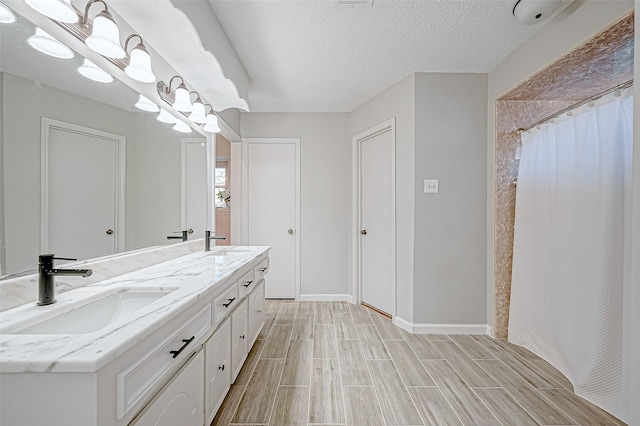 bathroom featuring vanity, a textured ceiling, and walk in shower