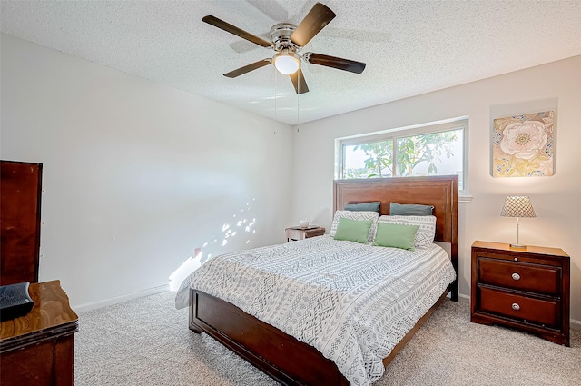 bedroom with a textured ceiling, light colored carpet, and ceiling fan