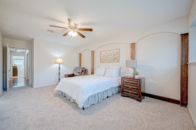 carpeted bedroom featuring ceiling fan and a textured ceiling