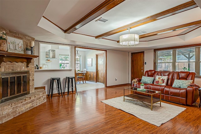 living room with hardwood / wood-style flooring, a wealth of natural light, and a brick fireplace