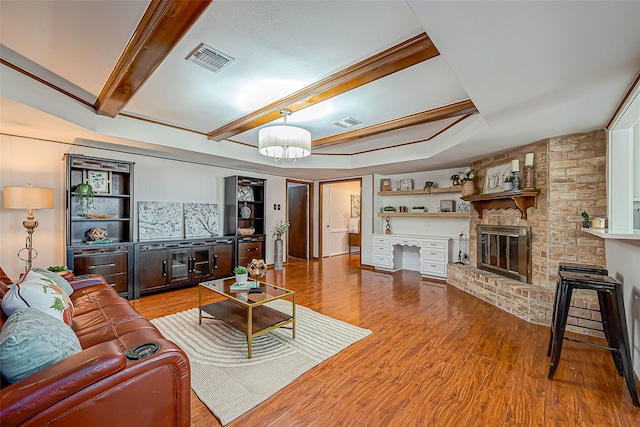 living room with wood-type flooring, a brick fireplace, and beam ceiling