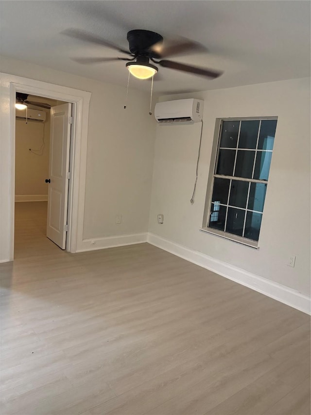 unfurnished room featuring ceiling fan, light hardwood / wood-style floors, and a wall mounted air conditioner