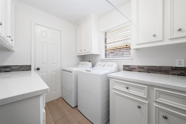 laundry room featuring washing machine and dryer, cabinet space, and wood tiled floor