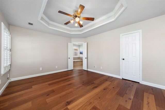 unfurnished bedroom featuring a raised ceiling, ceiling fan, dark hardwood / wood-style flooring, and crown molding