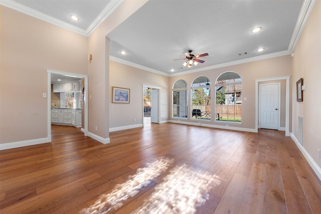 unfurnished living room featuring light wood-type flooring, baseboards, and ornamental molding