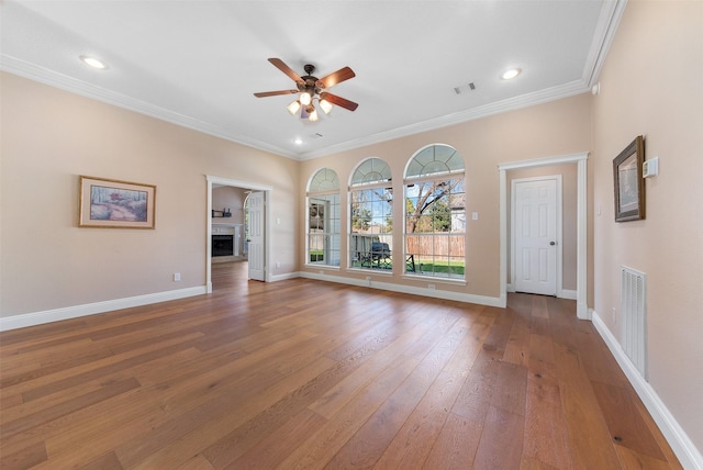 unfurnished living room with baseboards, ceiling fan, ornamental molding, hardwood / wood-style floors, and a fireplace