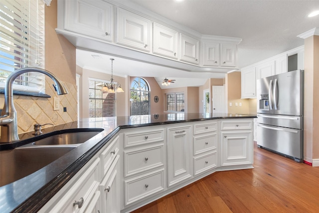 kitchen featuring tasteful backsplash, white cabinetry, a sink, wood finished floors, and stainless steel fridge