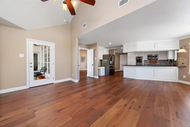 unfurnished living room featuring hardwood / wood-style floors, ceiling fan, sink, and vaulted ceiling