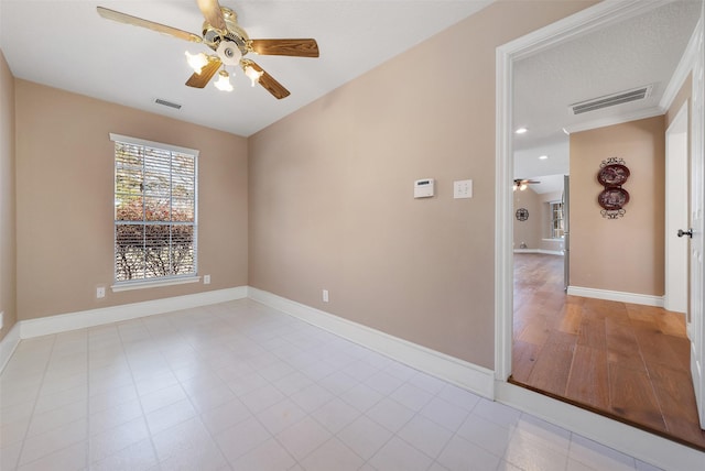 empty room featuring baseboards, visible vents, and a ceiling fan