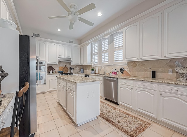 kitchen featuring white cabinetry, a kitchen island, light stone countertops, and appliances with stainless steel finishes