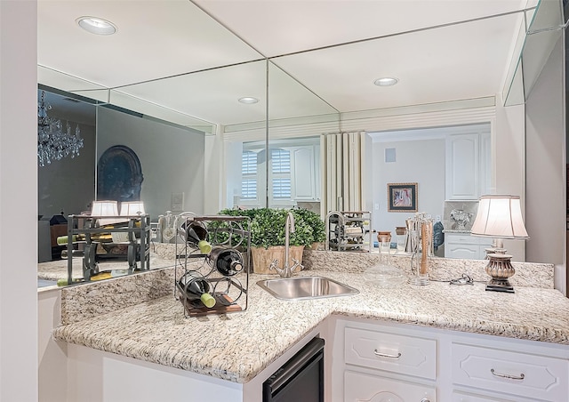 kitchen with white cabinets, light stone countertops, dishwasher, and sink