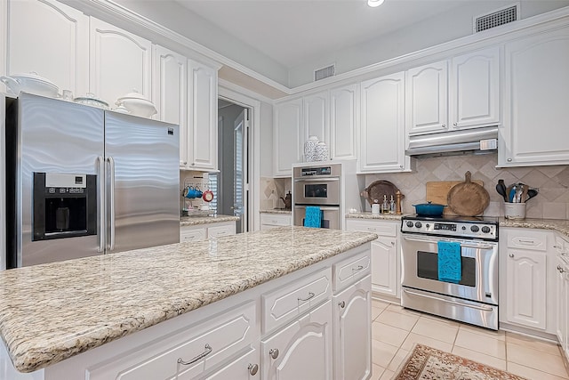 kitchen featuring tasteful backsplash, white cabinets, light tile patterned floors, and appliances with stainless steel finishes