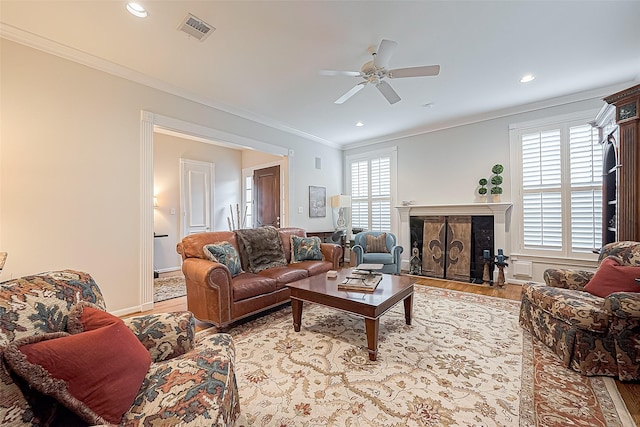 living room featuring a high end fireplace, light hardwood / wood-style floors, plenty of natural light, and ornamental molding