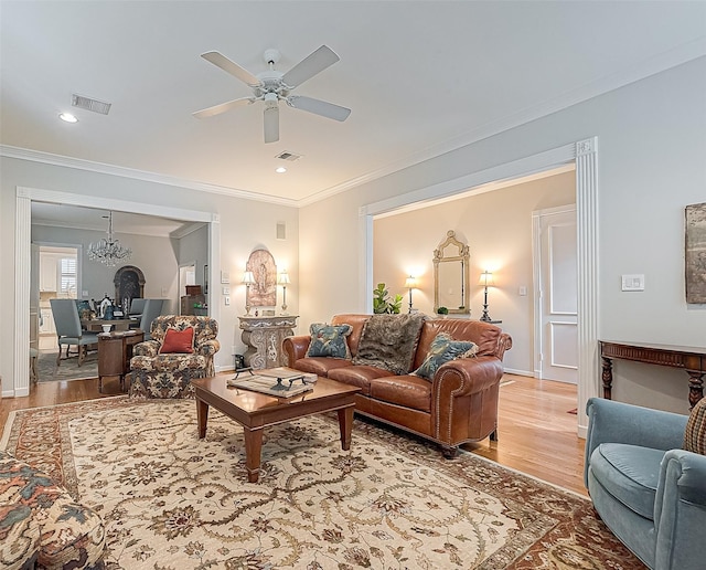 living room with ceiling fan with notable chandelier, light hardwood / wood-style flooring, and ornamental molding